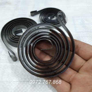 Lò xo máy khoan bàn (bản rộng ~12mm, thép dày 1.2mm, đường kính ~73mm)