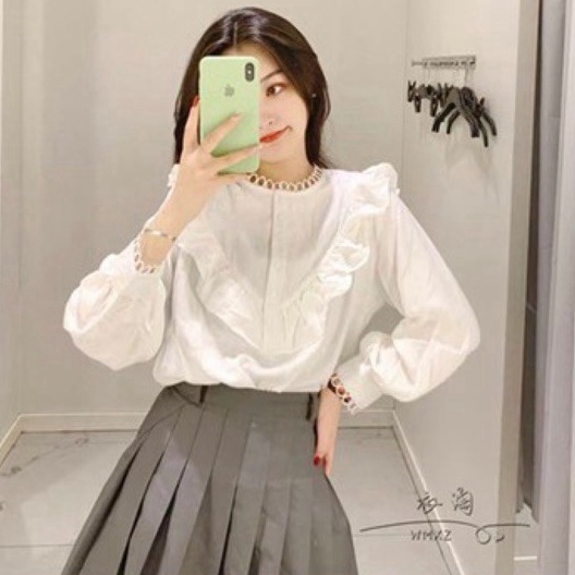 Áo sơ mi trắng cổ bèo dài tay bồng phối viền ren.