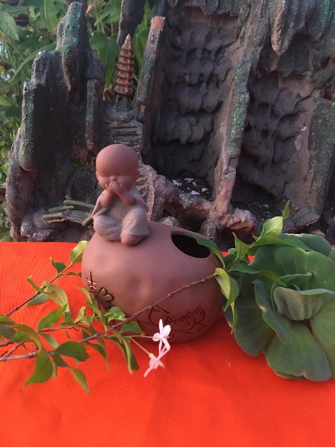 Chú tiểu ngồi trên tảng đá có thể cắm hoa , cắm bút