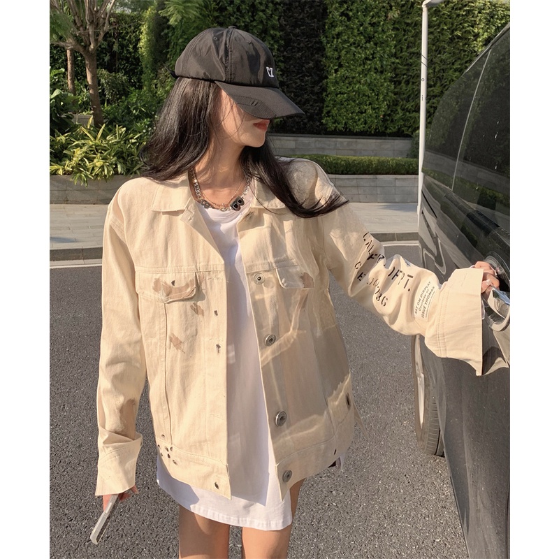 Áo khoác denim màu trắng sữa có vệt màu loang in chữ sau lưng phong cách cá tính