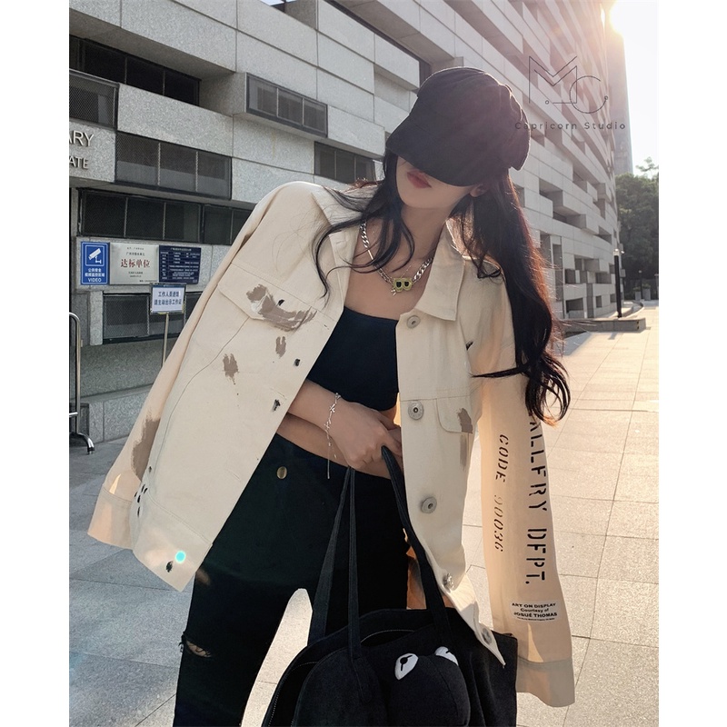 Áo khoác denim màu trắng sữa có vệt màu loang in chữ sau lưng phong cách cá tính