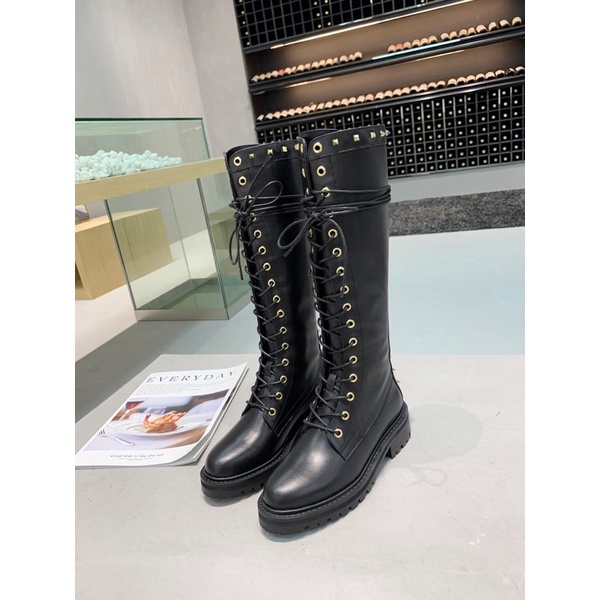 Bốt cao cổ Valentino thiết kế dây thắt cực dài nút xỏ dây màu vàng đồng tạo điểm nhấn sáng cho đôi bốt.