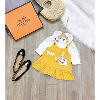 Set trang phục bé gái gồm áo thun trắng dài tay cổ cánh sen, chất thun cotton và váy yếm màu vàng hình thỏ đáng yêu