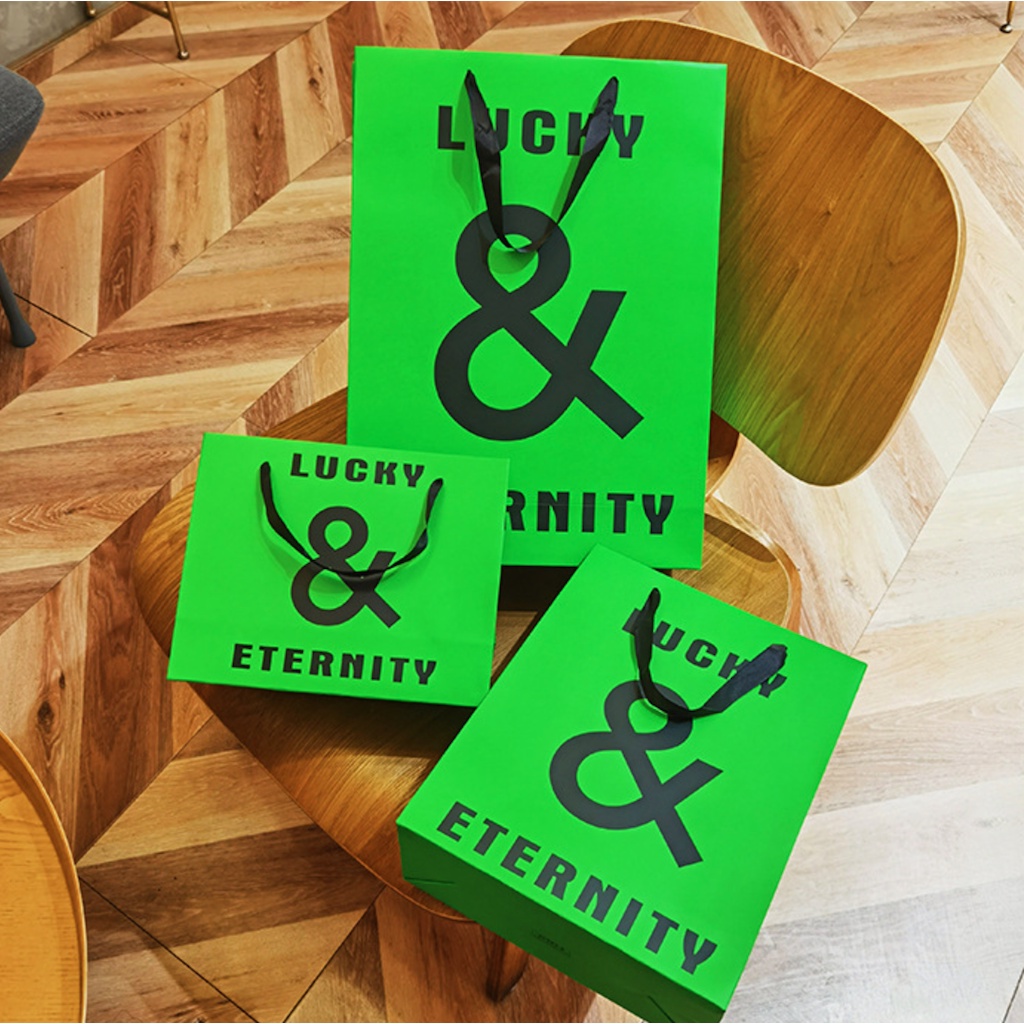 Túi giấy bìa cứng xanh logo đen "LUCKY & ETERNITY", quai vải mềm