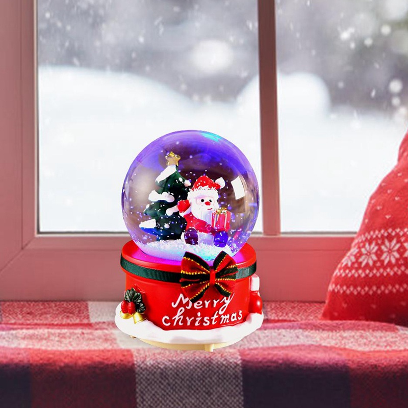 Hộp nhạc có hàng chữ "Merry Christmas" và quả cầu pha lê chứa ông già Noel