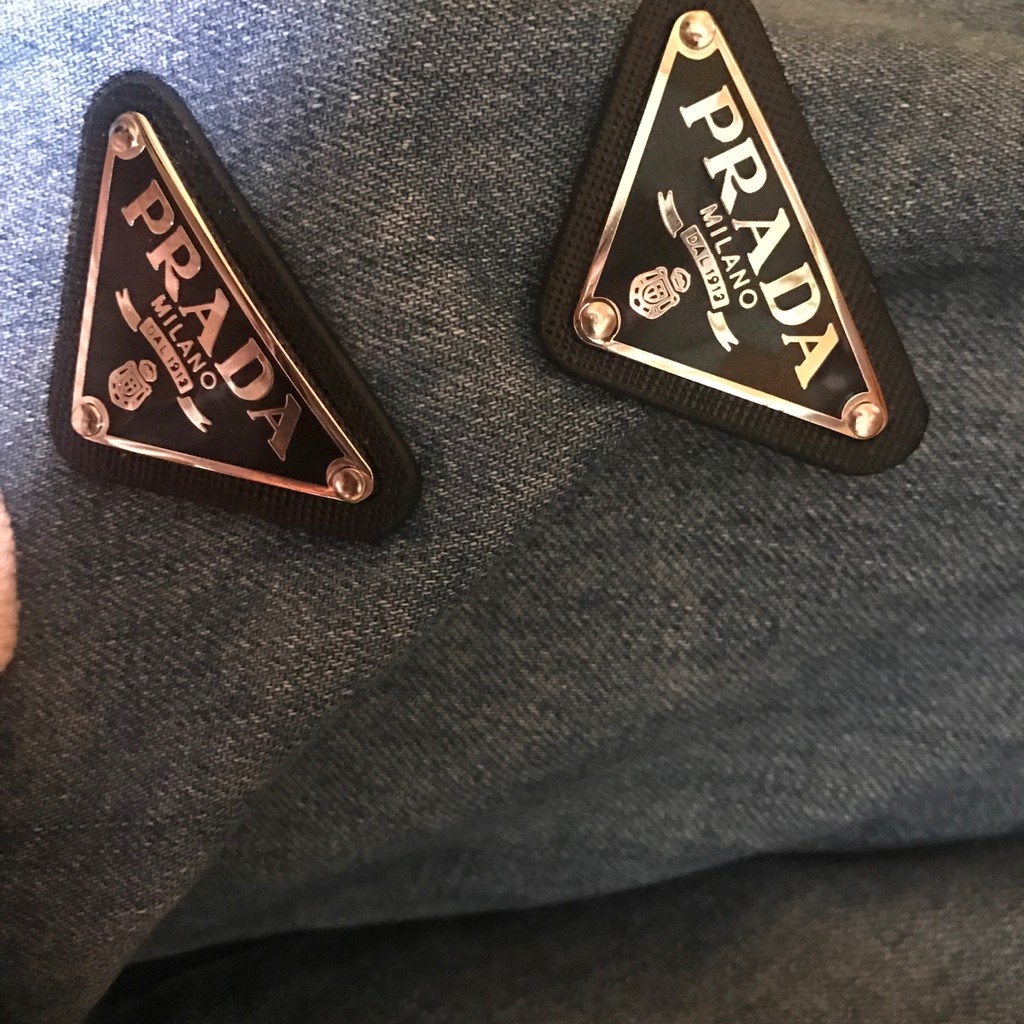 Ghim cài áo hình tam giác biểu tượng Prada dùng để trang trí