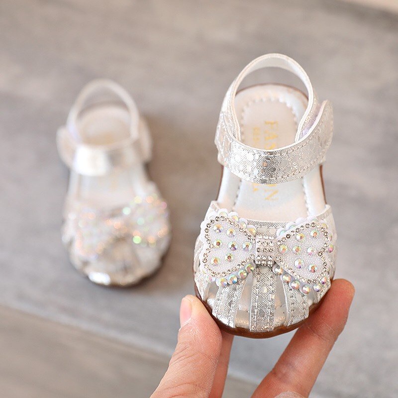 Dép sandal tập đi bé gái - Dép rọ tập đi cho bé phối nơ đá xắn chống vấp đế cao su mềm mã A9