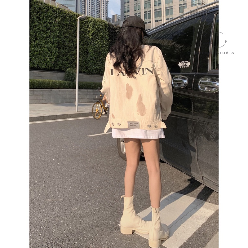 Áo khoác denim màu trắng sữa có vệt màu loang in chữ sau lưng phong cách cá tính