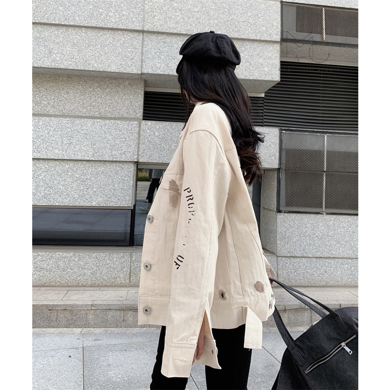 Áo khoác denim màu trắng sữa có vệt màu loang in chữ sau lưng phong cách cá tính