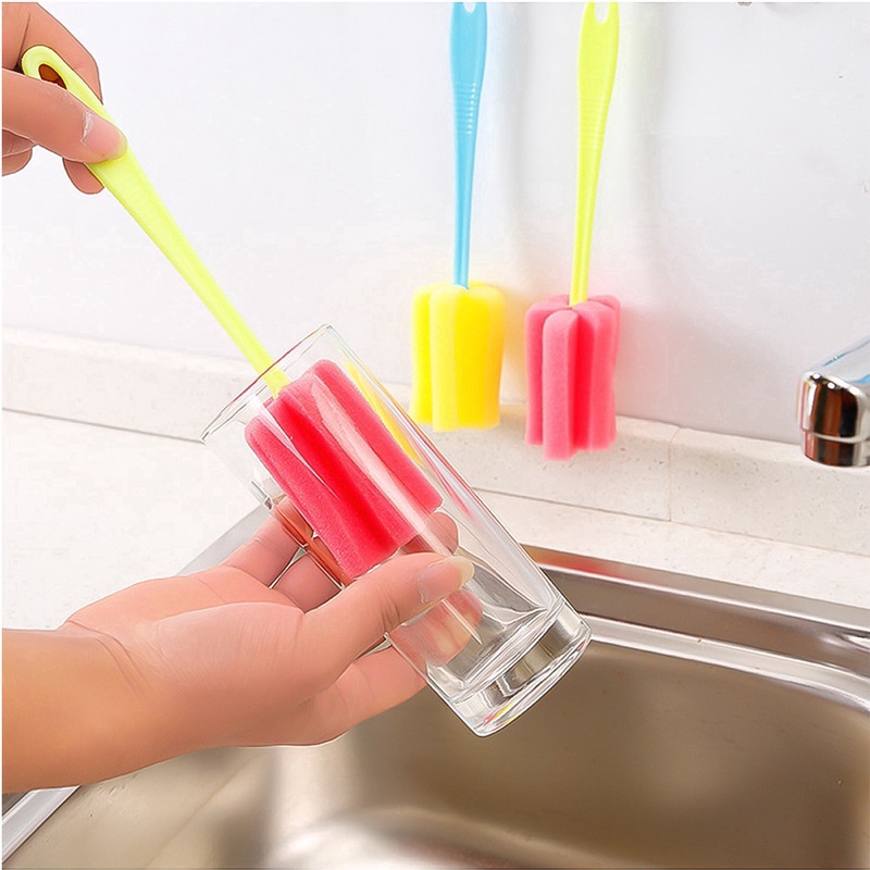 Bàn chải bọt biển dùng lau chùi với ly thủy tinh dùng trong nhà bếp