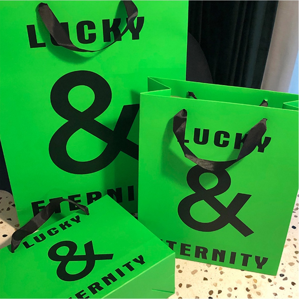 Túi giấy bìa cứng xanh logo đen "LUCKY & ETERNITY", quai vải mềm