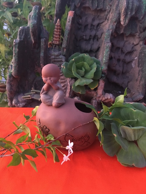 Chú tiểu ngồi trên tảng đá có thể cắm hoa , cắm bút