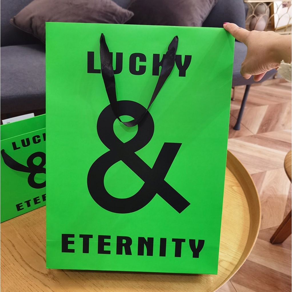 Túi giấy bìa cứng xanh logo đen "LUCKY & ETERNITY", quai vải mềm