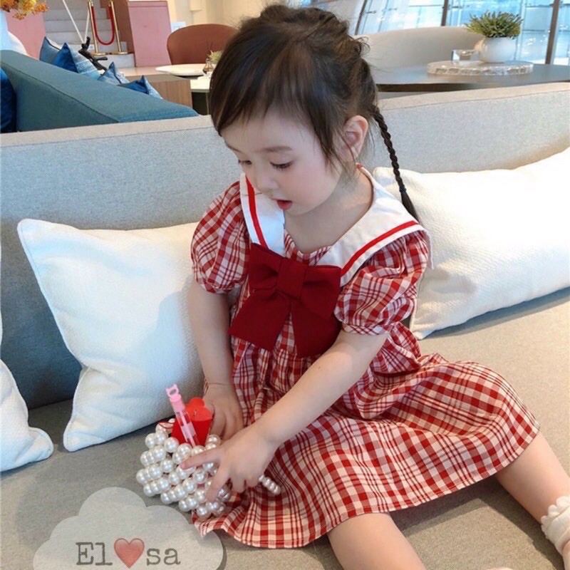 Váy caro đính kèm nơ đỏ bé gái