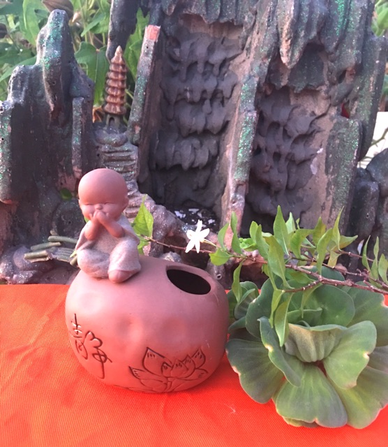 Chú tiểu ngồi trên tảng đá có thể cắm hoa , cắm bút