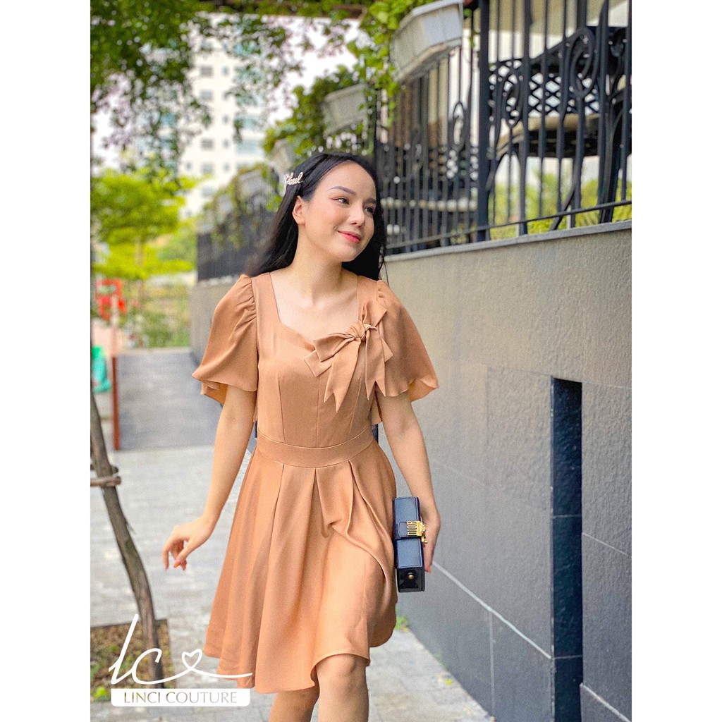Váy LinCI nơ nâu, váy cổ vuông ôm xòe nhẹ nhàng thanh lịch.
