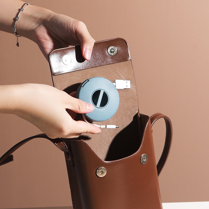 Portable mobile phone charging cable winder for carrying data cables that can be rotated to organize the storage box
