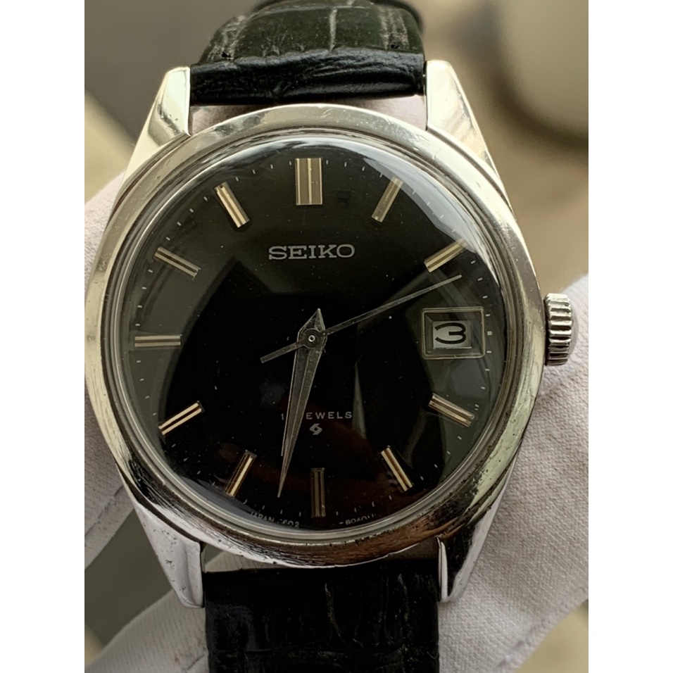 Đồng hồ nam SEIKO cơ cót 17 jewles, có ô cửa lịch, mặt màu đen, dây da thiết kế đơn giản của Nhật