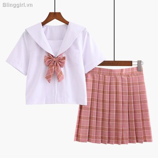 Bộ đồ đồng phục học sinh Nhật Bản với áo sơ mi trắng đính nơ và chân váy sọc ca rô màu hồng kiểu dáng đơn giản
