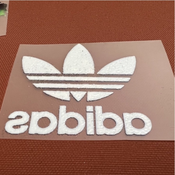 - Logo Adidas nhiều màu in trực tiếp lên vải bằng bàn ủi, bàn là