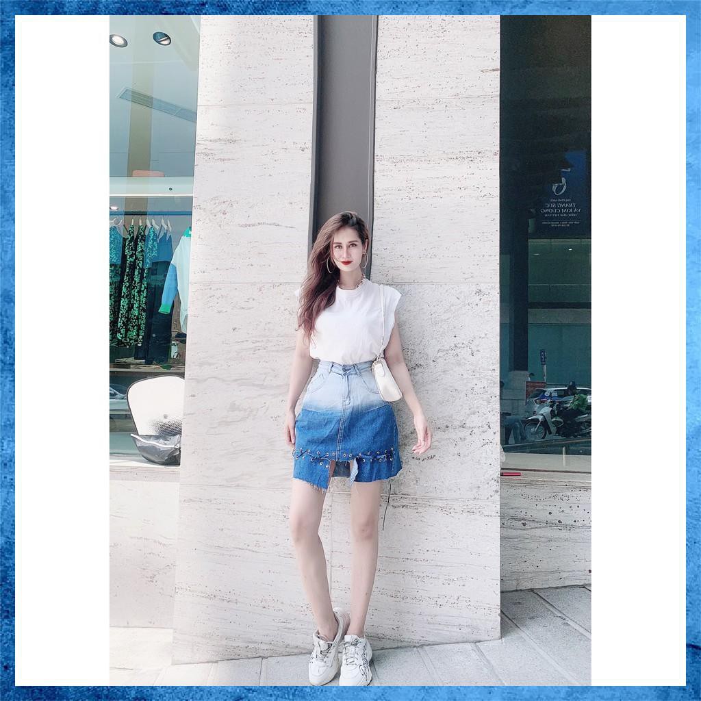 Chân váy denim ngắn, cạp cao loang màu túi chéo, gấu đan dây. Mã V9135