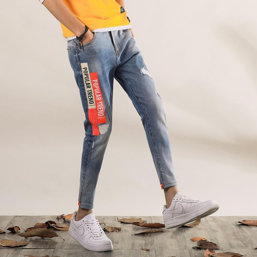 Quần jean nam xanh nhạt ống bó cao cấp TC với thiết kế rách xước kết hợp với logo đen trắng trên ống quần phá cách