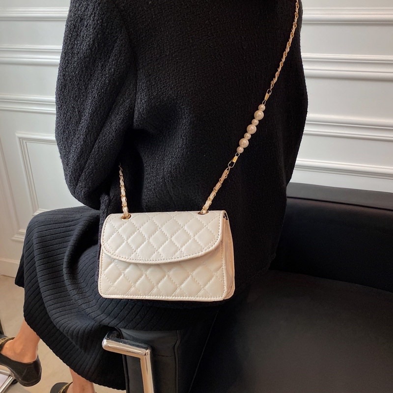 Túi xách nữ đeo chéo kẹp nách da thêu có nắp dây xích phối hạt ngọc nhân tạo.