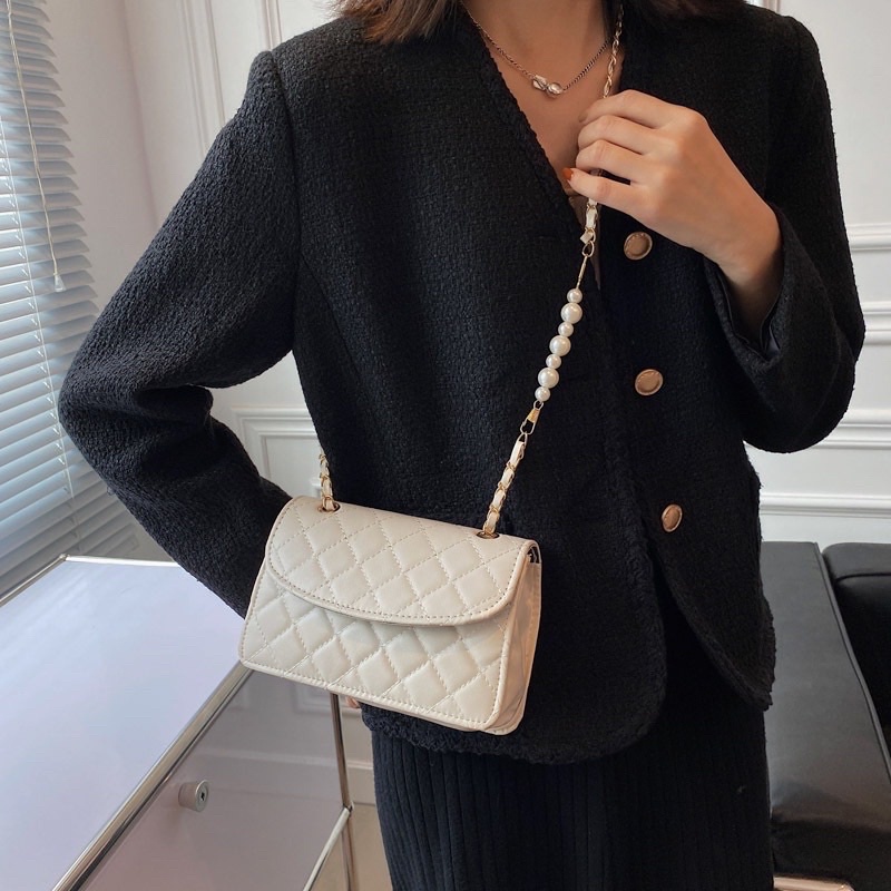 Túi xách nữ đeo chéo kẹp nách da thêu có nắp dây xích phối hạt ngọc nhân tạo.