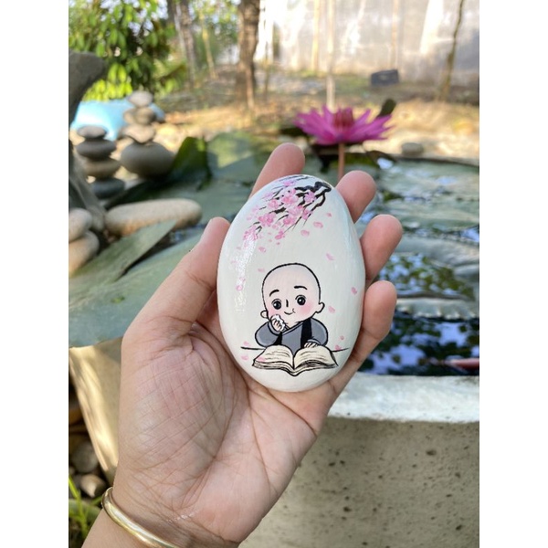 Chú tiểu hồn nhiên vẽ tay trên đá cuội.