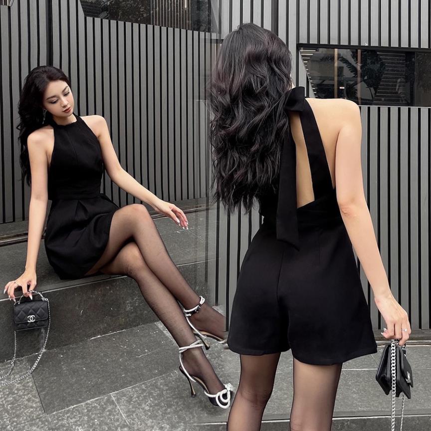 Jumpsuit đen cổ yếm hở lưng, dáng ngắn. Phần nơ rời, có thể mặc thành nhiều cách