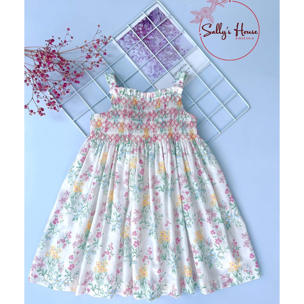 Đầm smock hai dây hoa chất vải cotton mềm, bên trong có lót boi mềm giấu đường an toàn cho da bé.