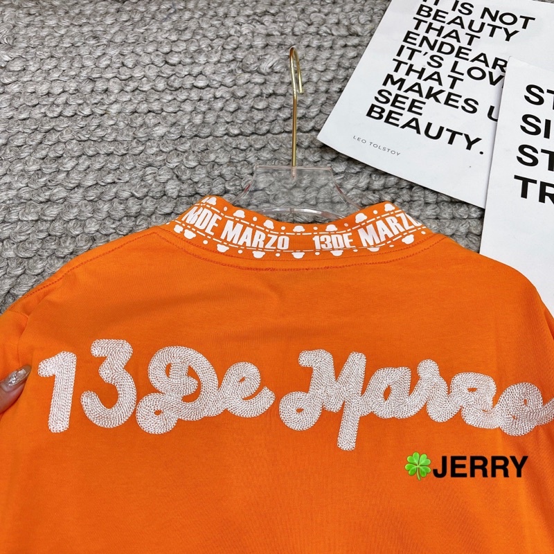 Áo phông 13de marzo cam tay đính gấu bông