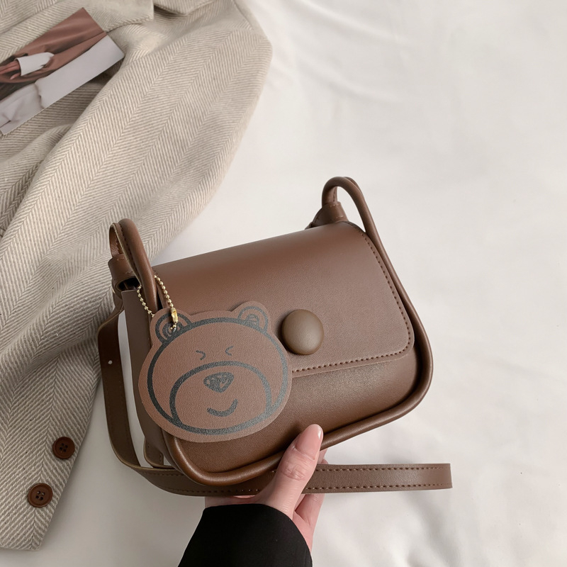 Túi xách nữ đeo chéo da trơn ngăn có khóa kéo kèm móc khóa gấu dễ thương có hai màu đen và nâu
