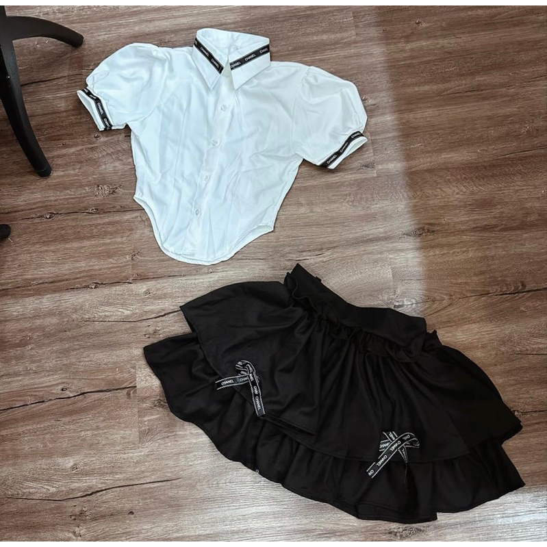 Sét áo cổ bẻ tay bồng viền đen kèm chân váy ngắn xếp tầng đính nơ