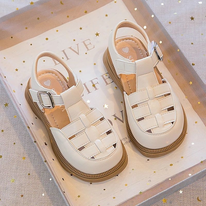 Sandal rọ da PU đan chéo đế mềm chống trơn trượt phòng cách hàn quốc cho bé gái đi học đi chơi QCCC