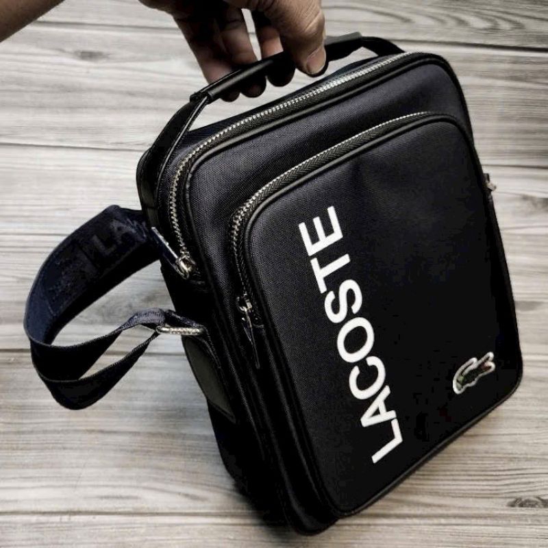 TÚI CHÉO NAM LA COS TE Logo Graphic,màu xanh navy, logo kim loại - mặt trước in chữ Lacoste, đẹp tinh tế xịn