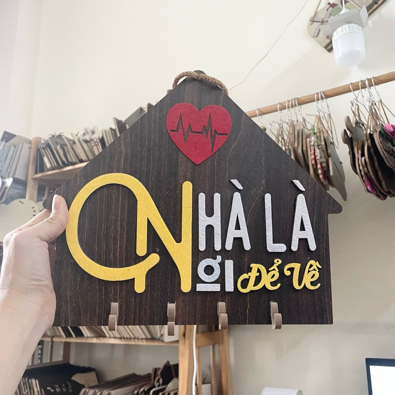 Bảng gỗ, tranh gỗ NHÀ LÀ NƠI ĐỂ VỀ hình ngôi nhà nền gỗ đen có móc treo chìa khoá tặng đinh 3 chân