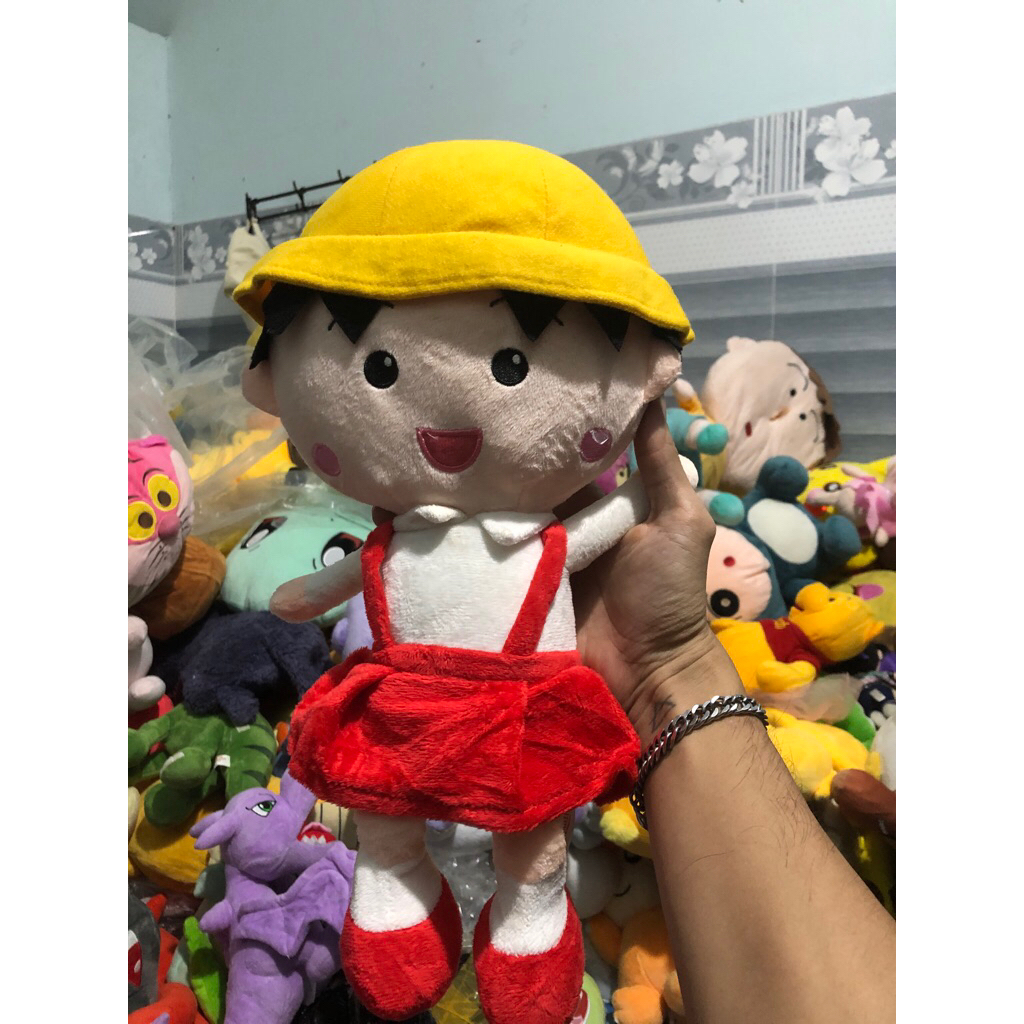 Gấu 2hand búp bê nhồi bông nhân vật Chibi Maruko-chan với chiếc mũ màu vàng đặc trưng.